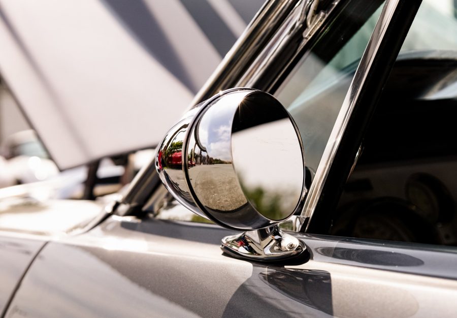 Chrome bullet side mirror reflecting the sky and parking lot