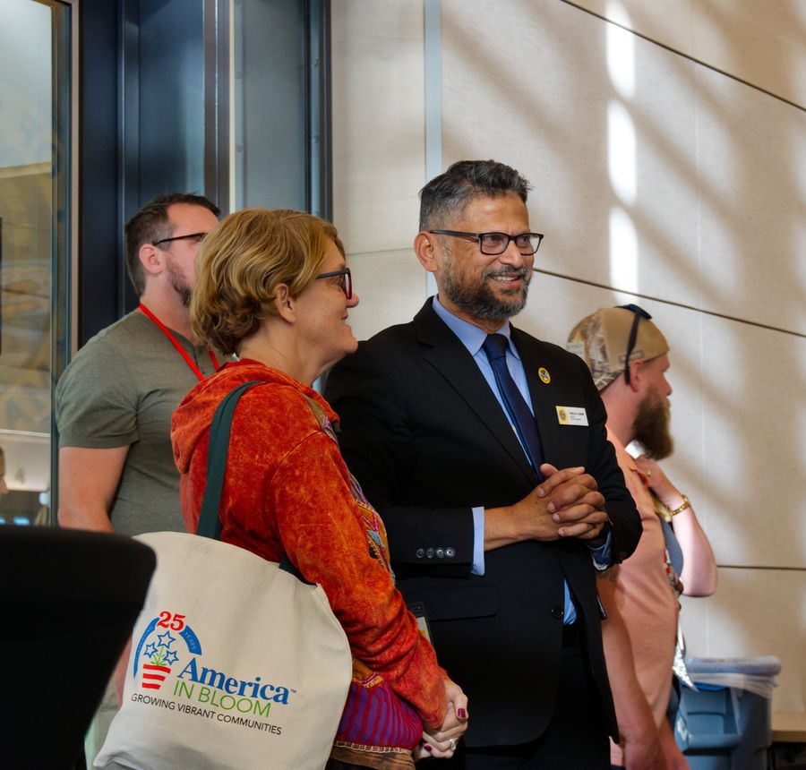 Two attendees sharing a laugh, one holding an America in Bloom tote bag