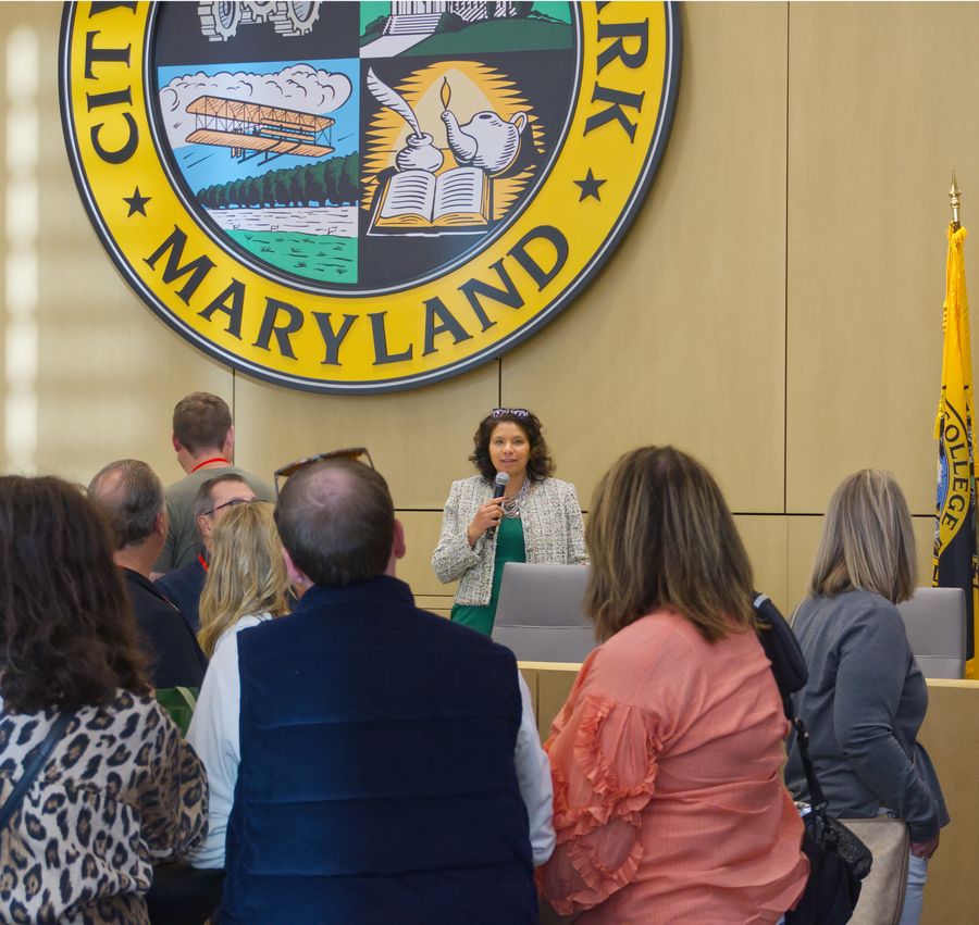 Speaker addressing a crowd beneath the City of College Park seal