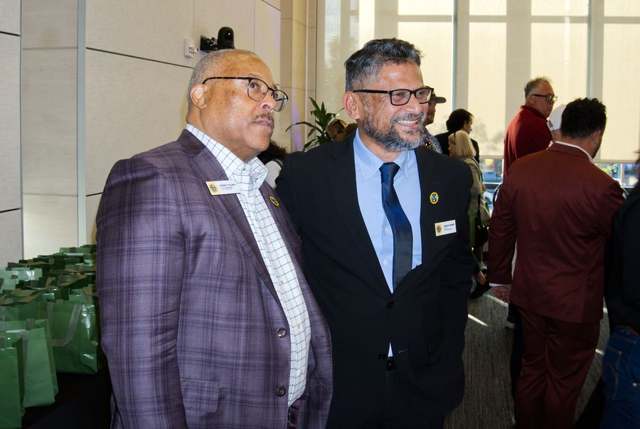Two men in suits smiling during an event