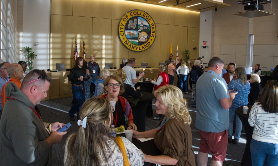 Crowd of guests mingling beneath the City of College Park seal