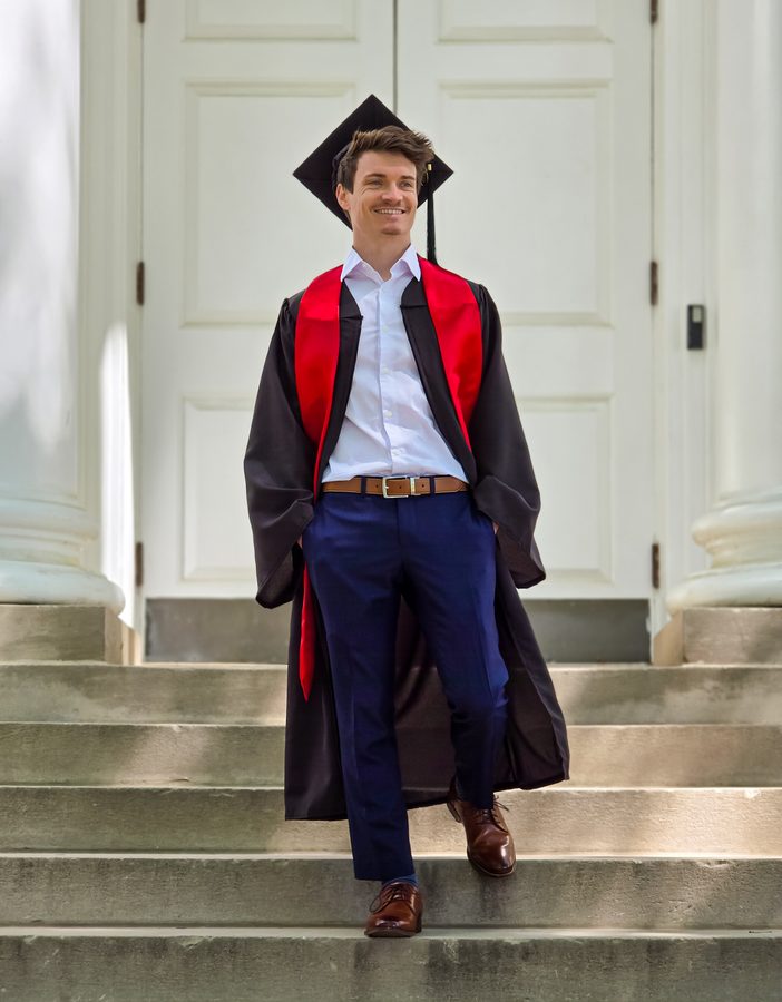 Graduate in cap and gown walking down white chapel steps