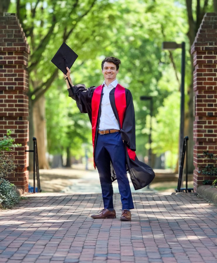 Graduate tossing his cap in the air on a brick campus walkway