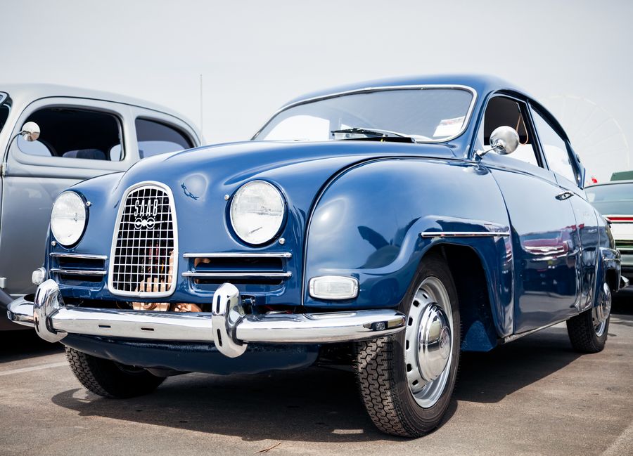 Navy classic Saab with chrome bumpers and grille parked at a car show